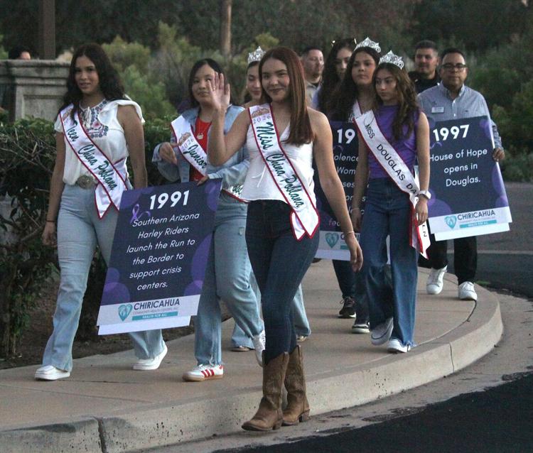 Bruce Whetten Prior to the vigil a walk took place from the YMCA on Pan American Avenue to the Douglas Police Department. Douglas China Poblana Juliana Padilla, center, carries a sign with a date of remembrance flanked by Bella Noriega, left, and Denise Briseno, right.Bruce Whetten Herald/Review